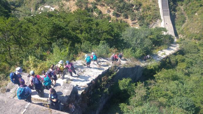 Group of trekkers walking down steep steps of Great Wall