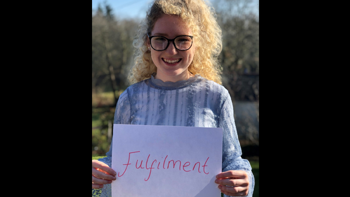 Young woman holding hand written sign that says fulfilment