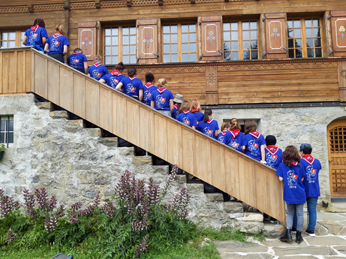 Girls standing along a staircase outside of Our Chalet, with backs to the camera